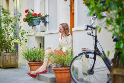 Frau sitzt zufrieden auf den Stufen vor ihrem Haus